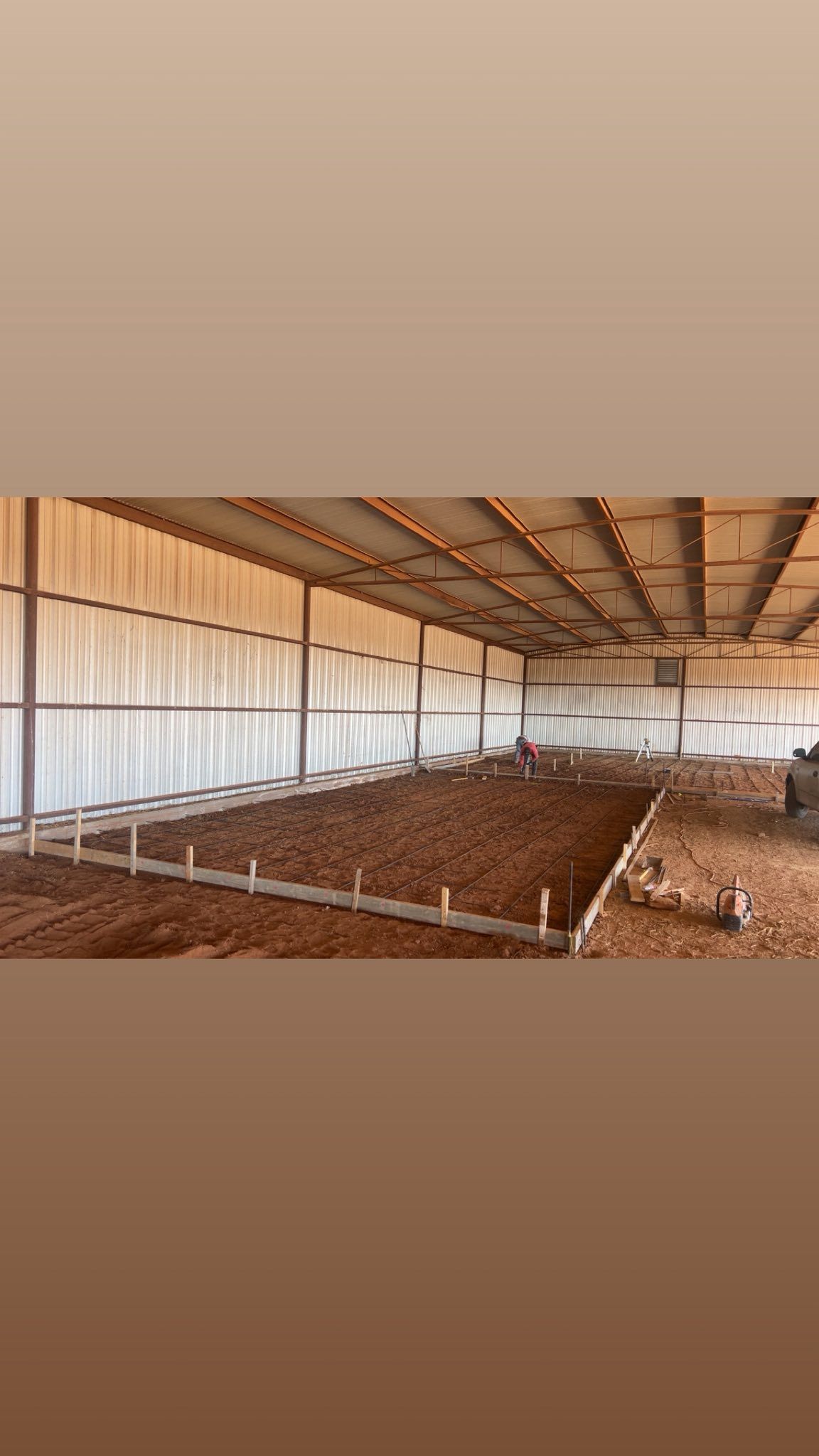 Indoor horse arena with dirt floor, wood barriers, and metal roof.