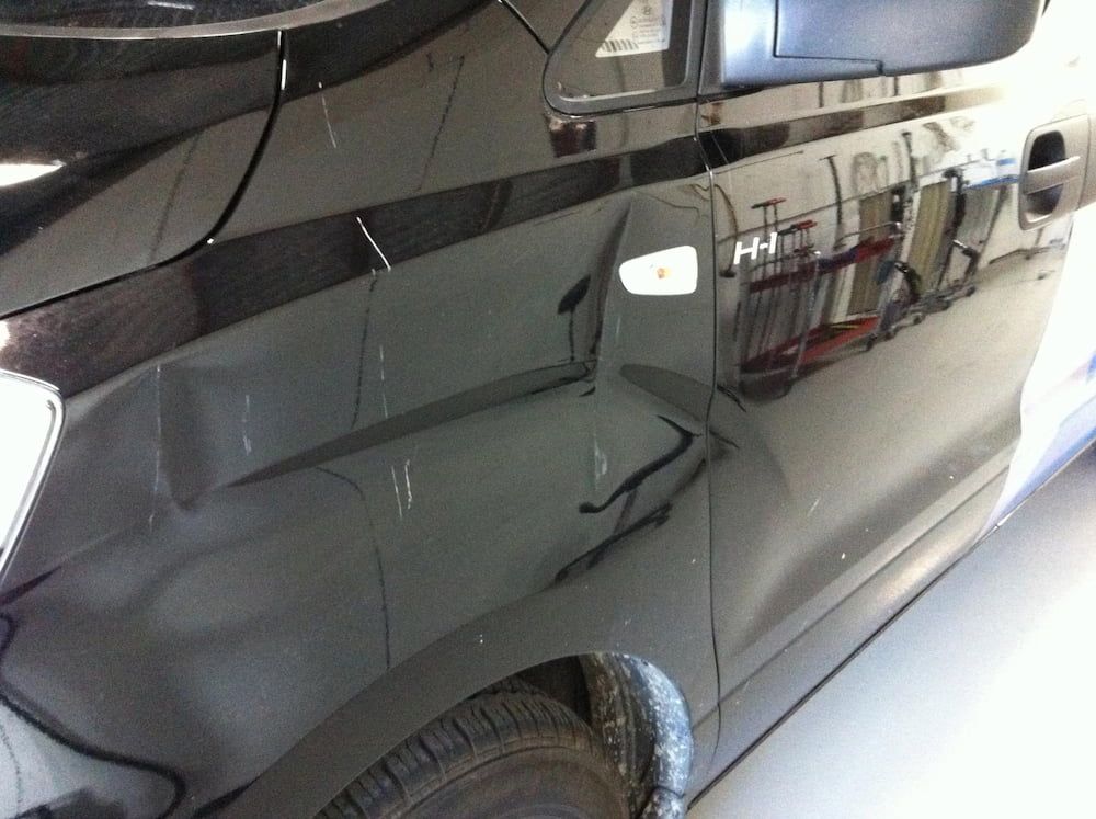 A Black Car is Parked in a Garage With the Door Open — Rapid Auto Dent In Ettalong, NSW