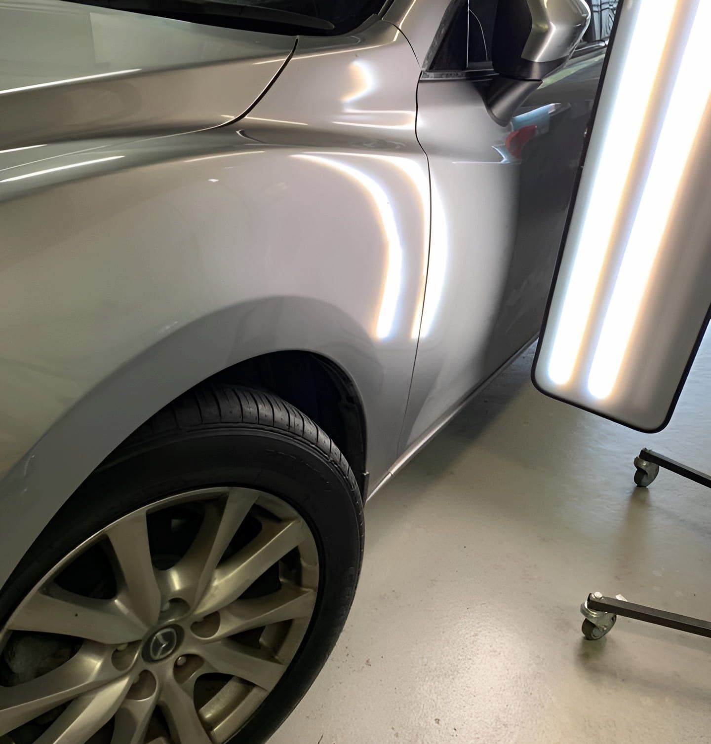 A Silver Car Is Sitting In A Garage Next To A PDR Light — Rapid Auto Dent In Wyong, NSW