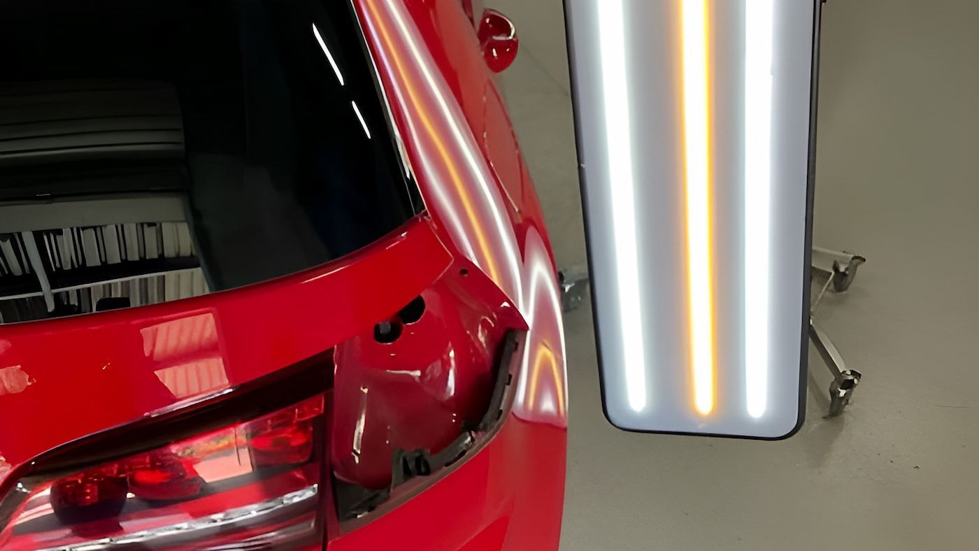 A Red Car With a Dent in the Back is Sitting Next to a Dent Board — Rapid Auto Dent In Avoca Beach, NSW