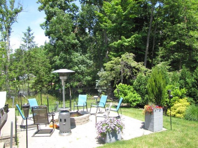 Patio with chairs around a fire pit in a lush green garden on a sunny day