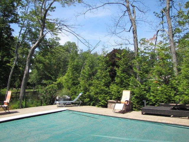 Backyard pool with lounge chairs and trees under a clear blue sky
