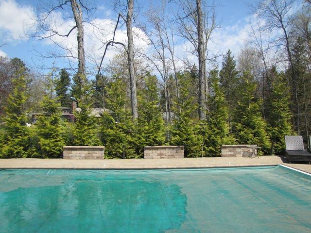 Turquoise swimming pool with stone benches and trees in the background