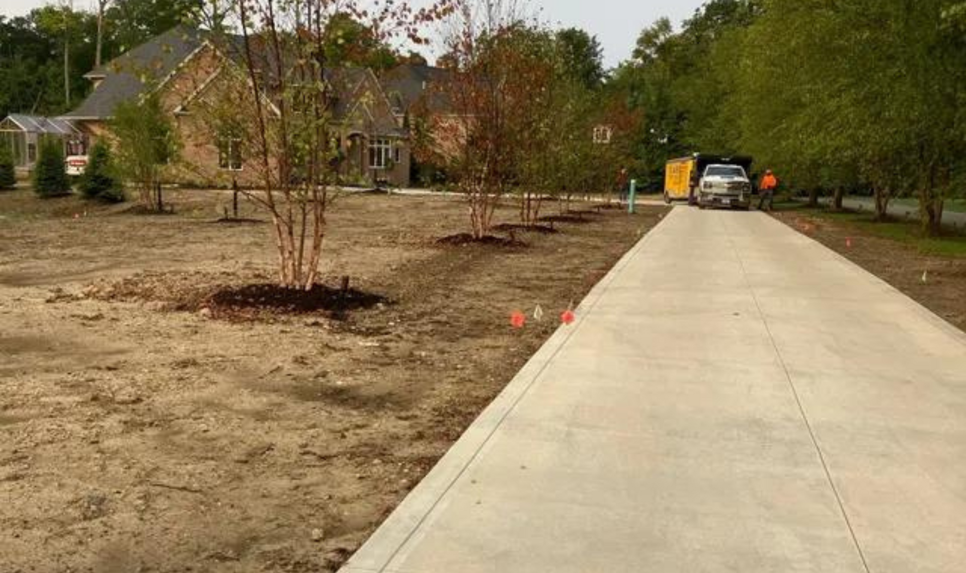 Driveway leading to a house, with dry landscaping and a car parked near the entrance.