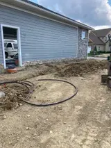 Backyard beside a house with dirt, a coiled hose, and a partially open side door