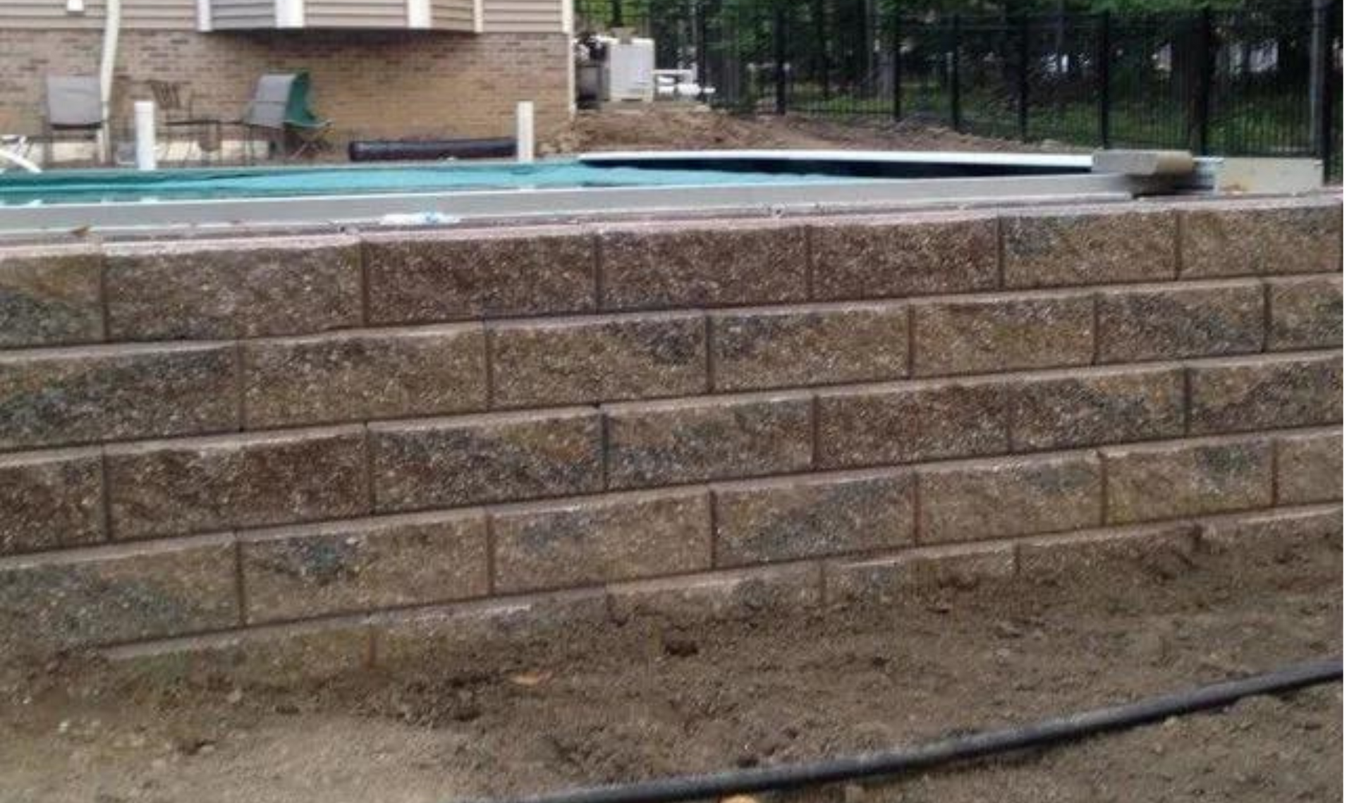 Stone retaining wall beside a swimming pool in a residential yard