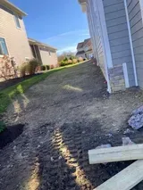 Gravel path between apartment buildings with muddy tire tracks and a white board in the foreground
