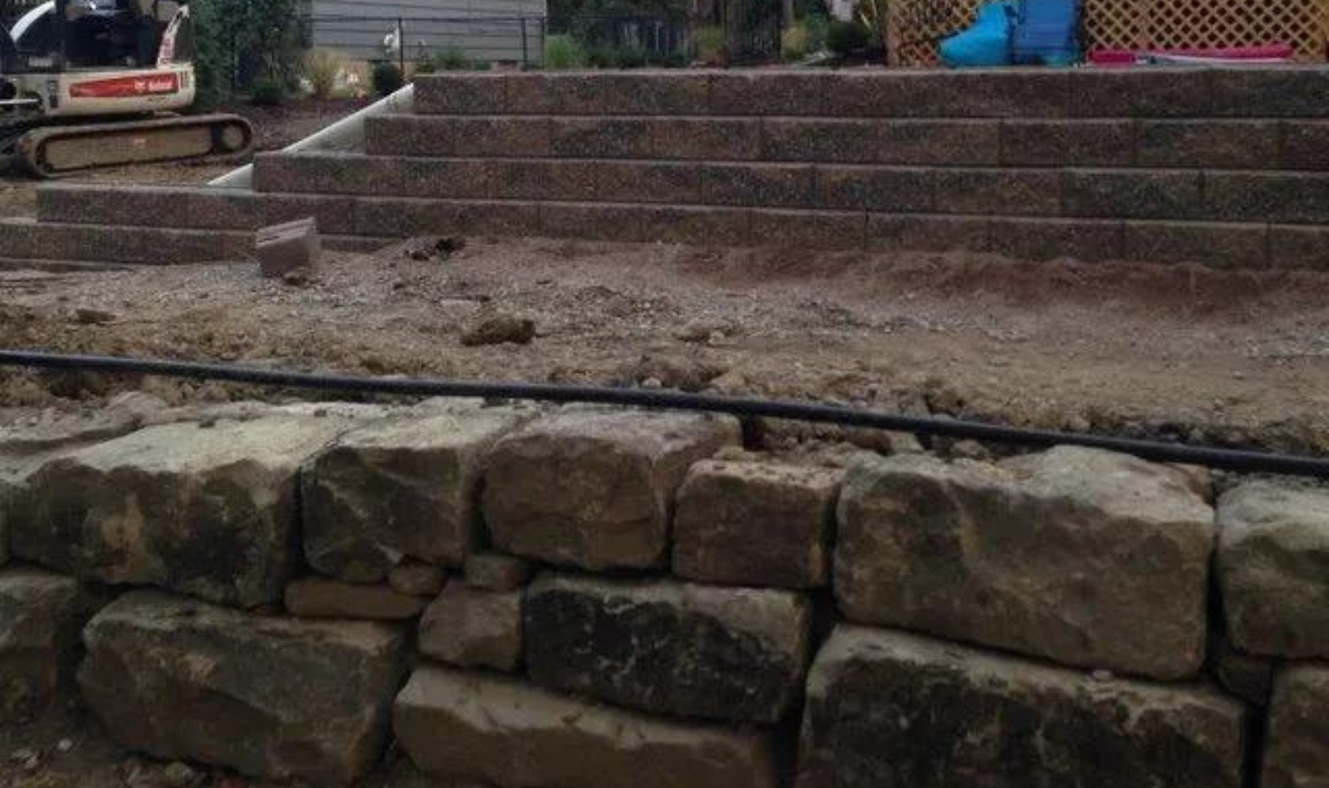 Stone steps and a low rock wall in an outdoor garden or yard setting