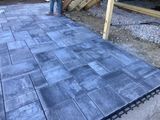 Gray interlocking patio pavers beside a yellow post and gravel edge