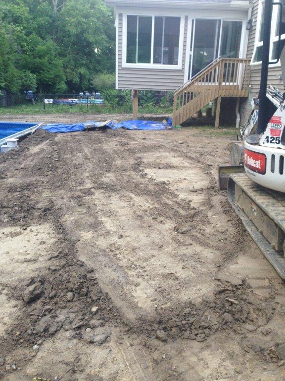 Mud-covered backyard under construction beside a house with a porch and a parked truck