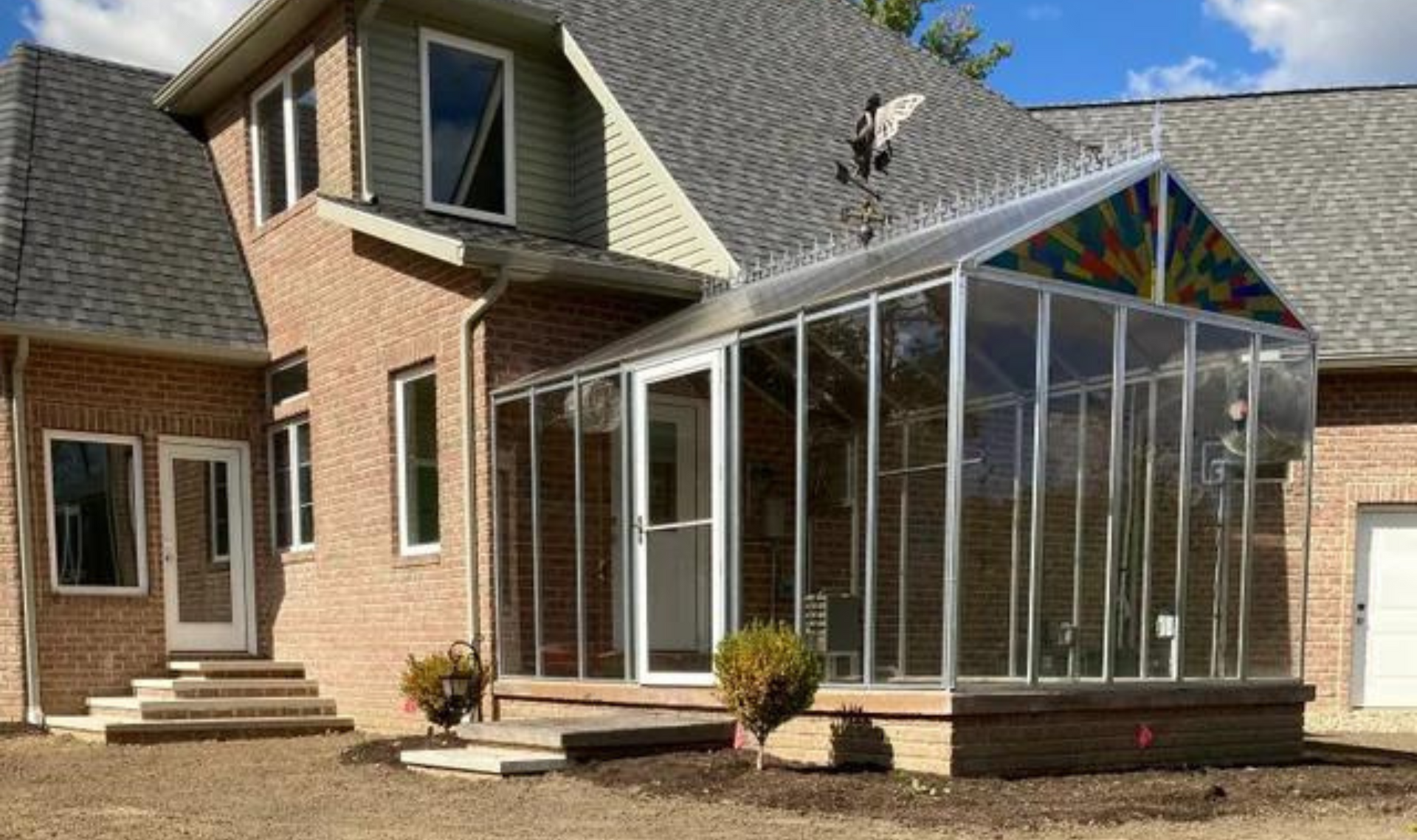 Brick house with a glass-enclosed sunroom and screened porch under construction