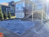 Backyard patio with a house, covered deck, and blue tarp over the ground