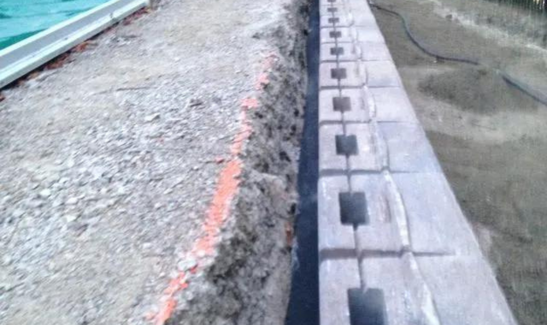 Seawall construction with concrete curb blocks beside rough gravel and water