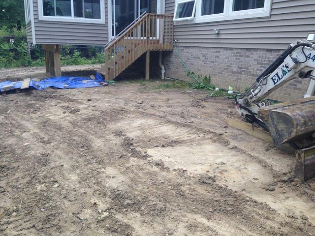 Backyard excavation area beside a house, with a stairway and an excavator bucket visible.