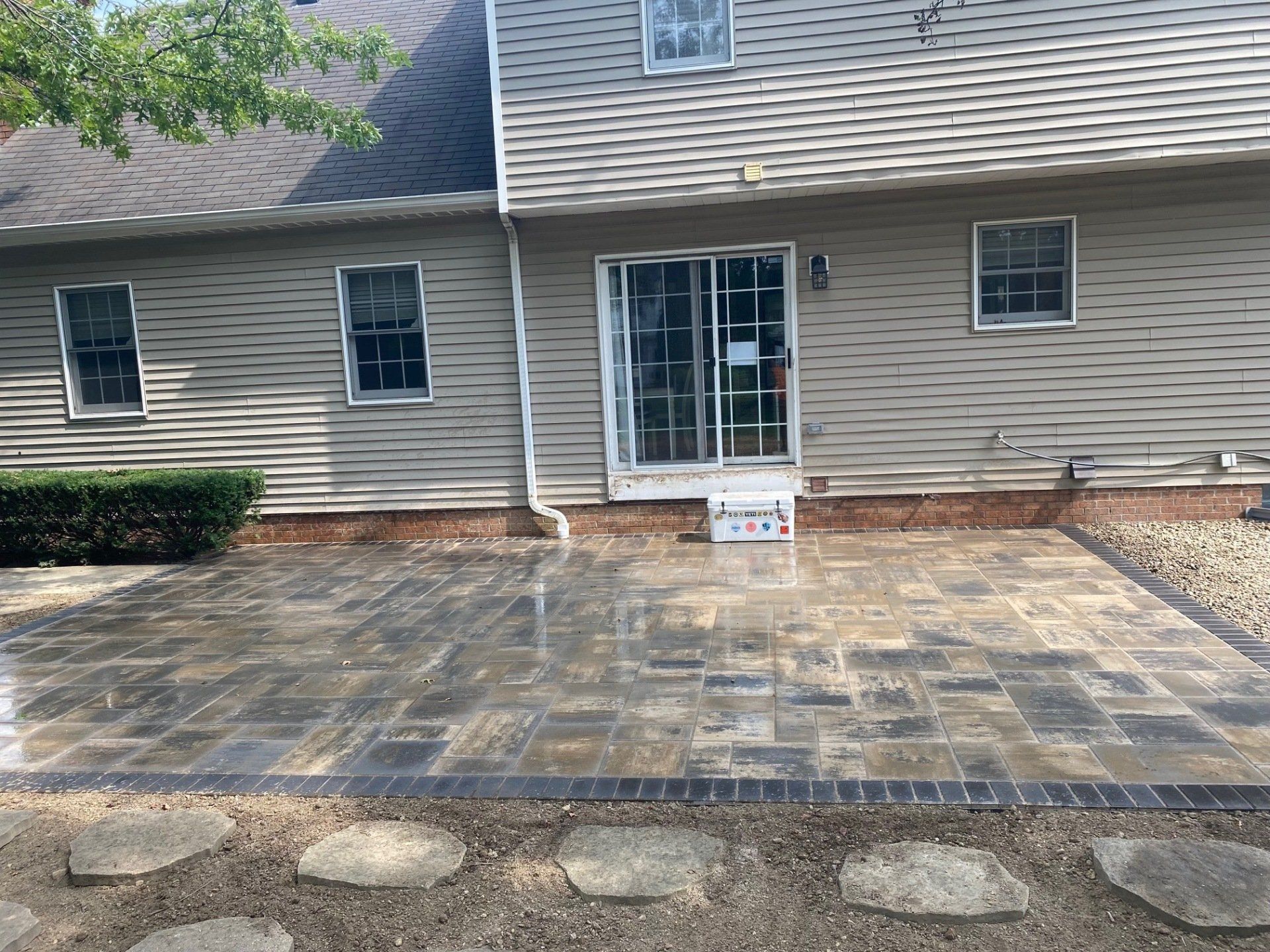 House exterior with stone patio and sliding glass door under a covered roof