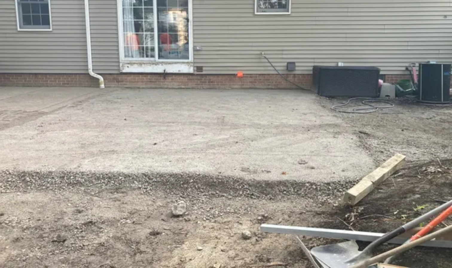 Gravel driveway under construction beside a house, with tools and materials in the foreground.