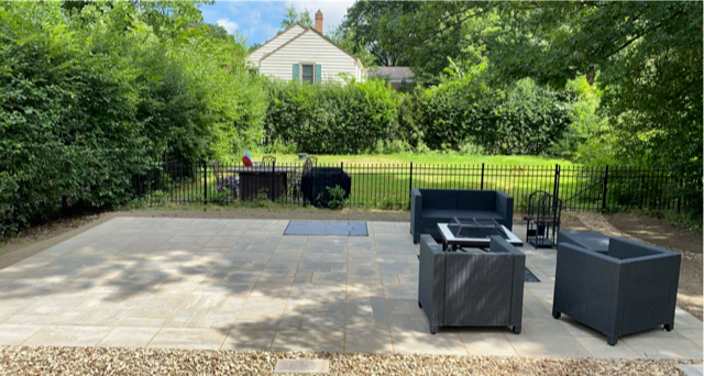 Patio with black outdoor furniture overlooking a green yard and a house in the background
