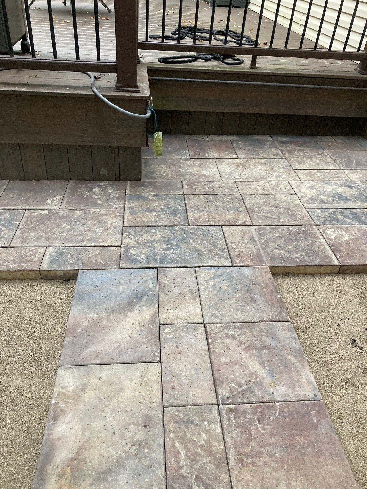 Stone patio leading to a wooden deck railing, with a small green bottle near the edge.