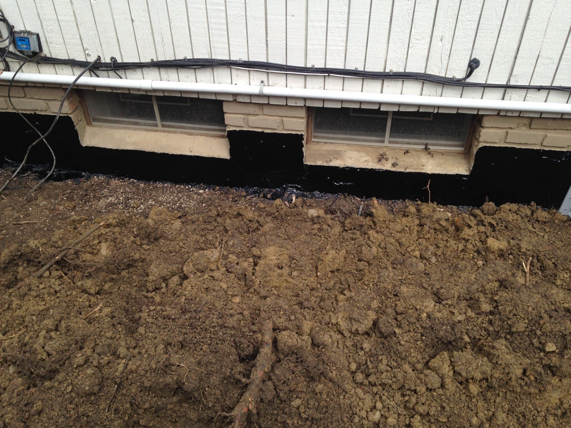Raised house foundation with open crawlspace above bare dirt ground