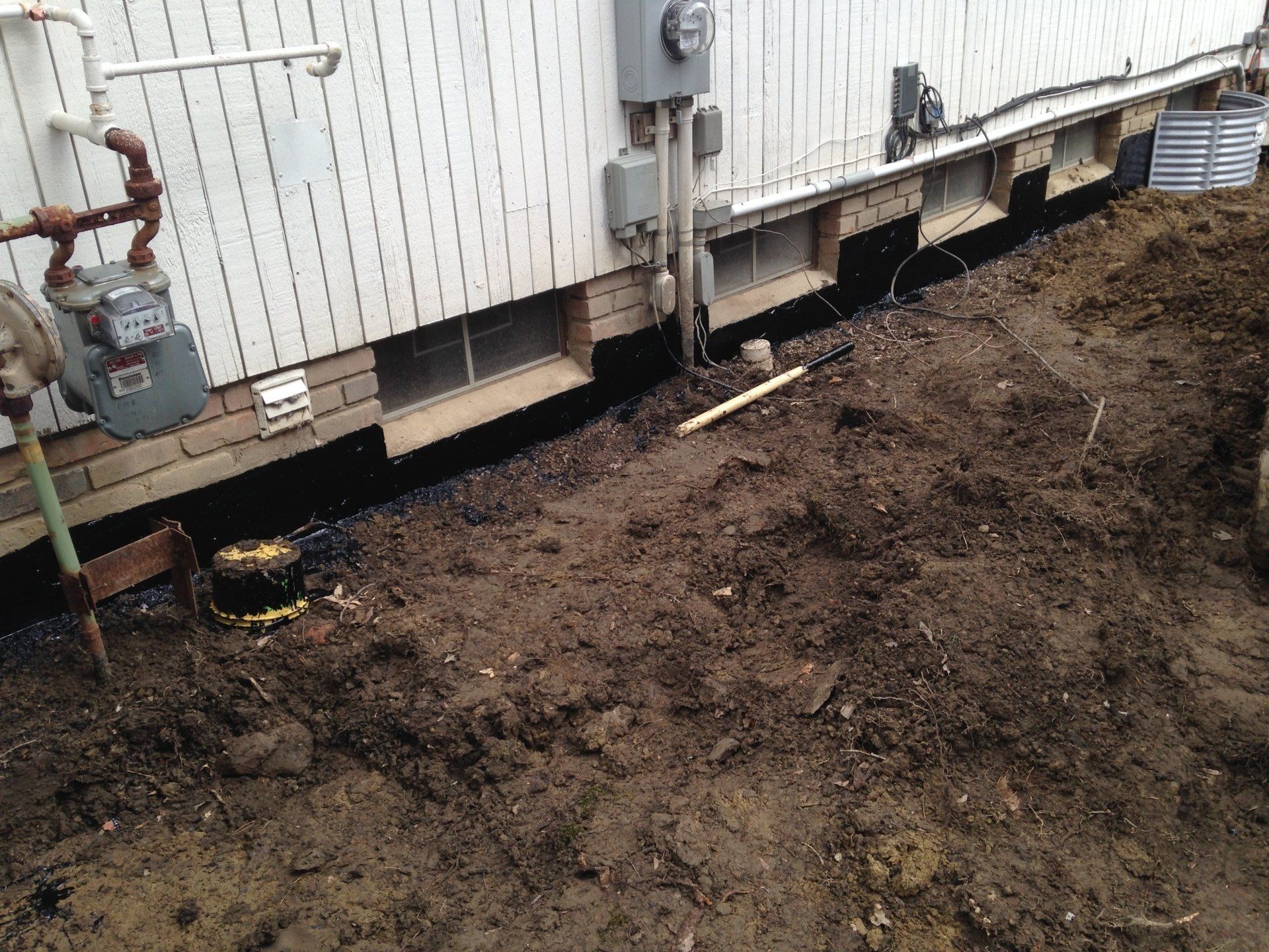 Bare yard beside a white trailer with utility boxes and exposed dirt ground