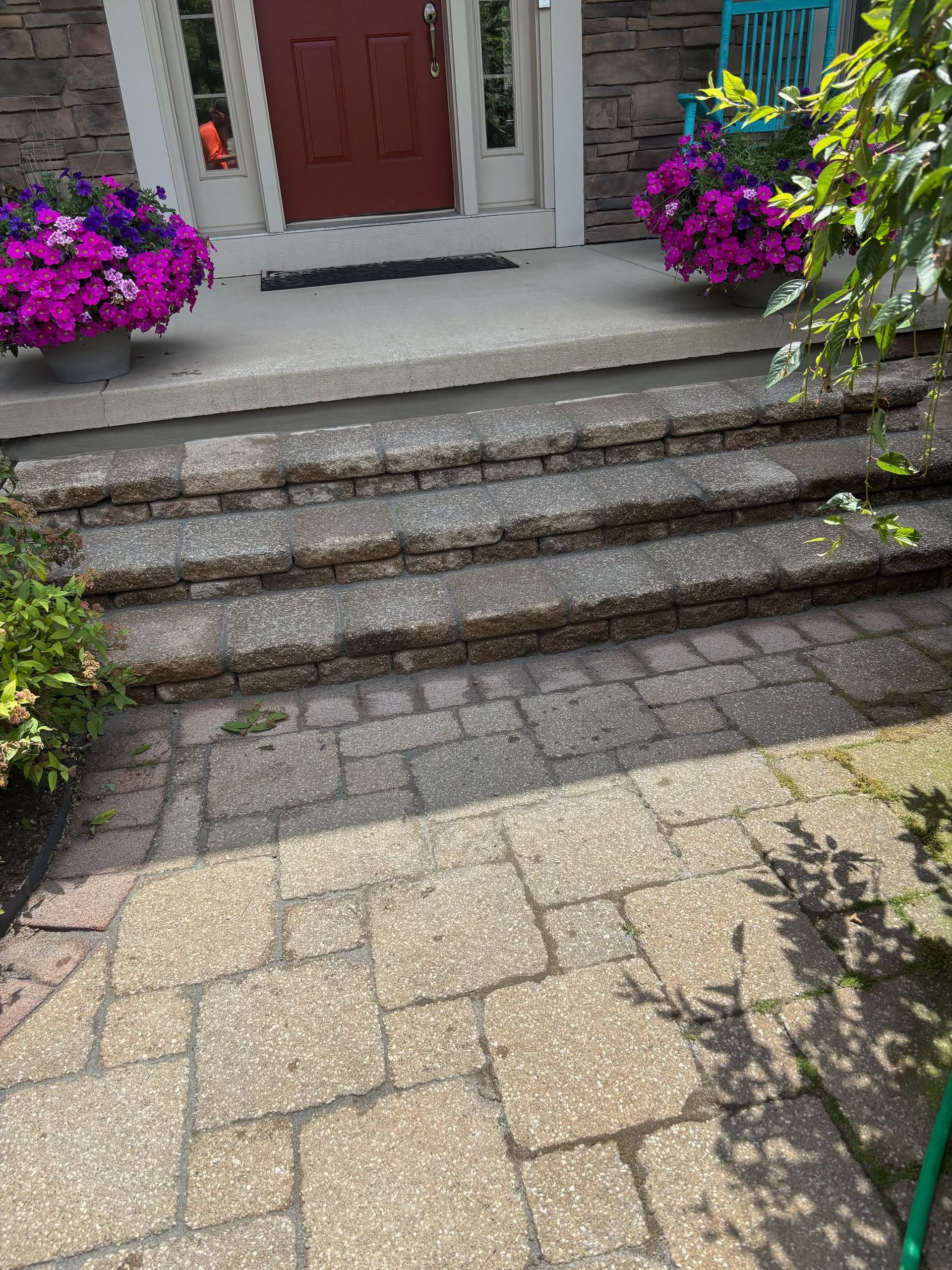 Front steps with purple flowers flanking a red door and stone pathway in front of a house