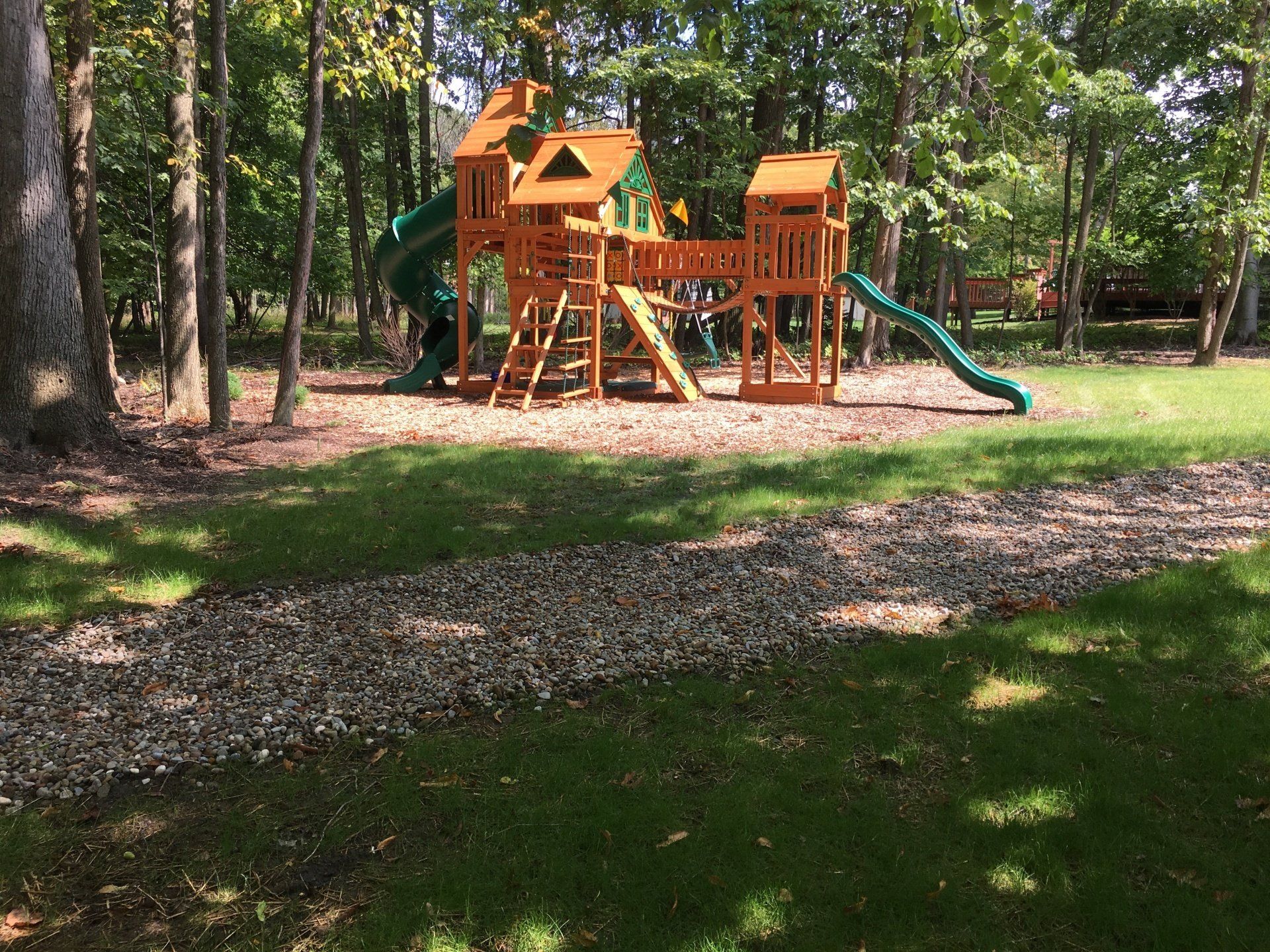 Wooden playground with slides and climbing structure in a wooded park