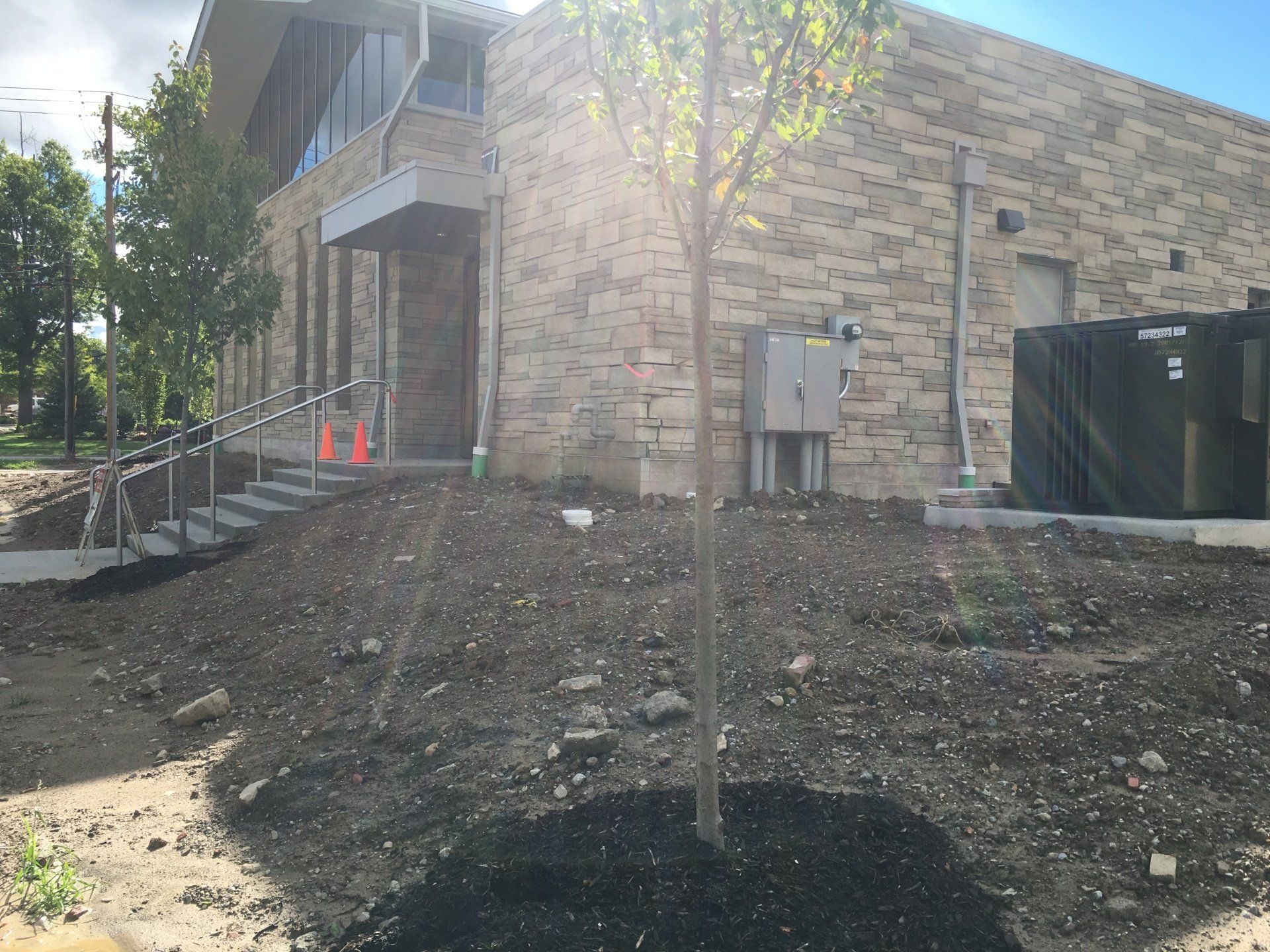 Apartment building under construction with stone exterior, dirt slope, and stairs on the left