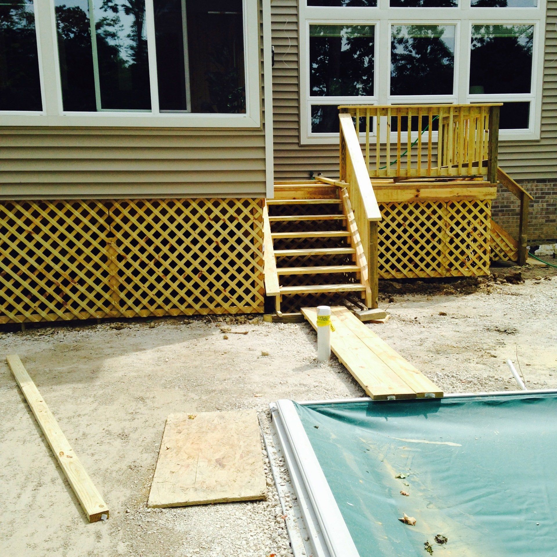 Backyard deck stairs with a wooden ramp leading to a covered pool area.