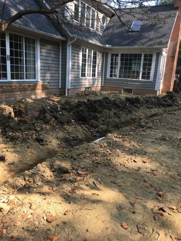 House front with exposed dirt and mulch area, showing a yard under renovation