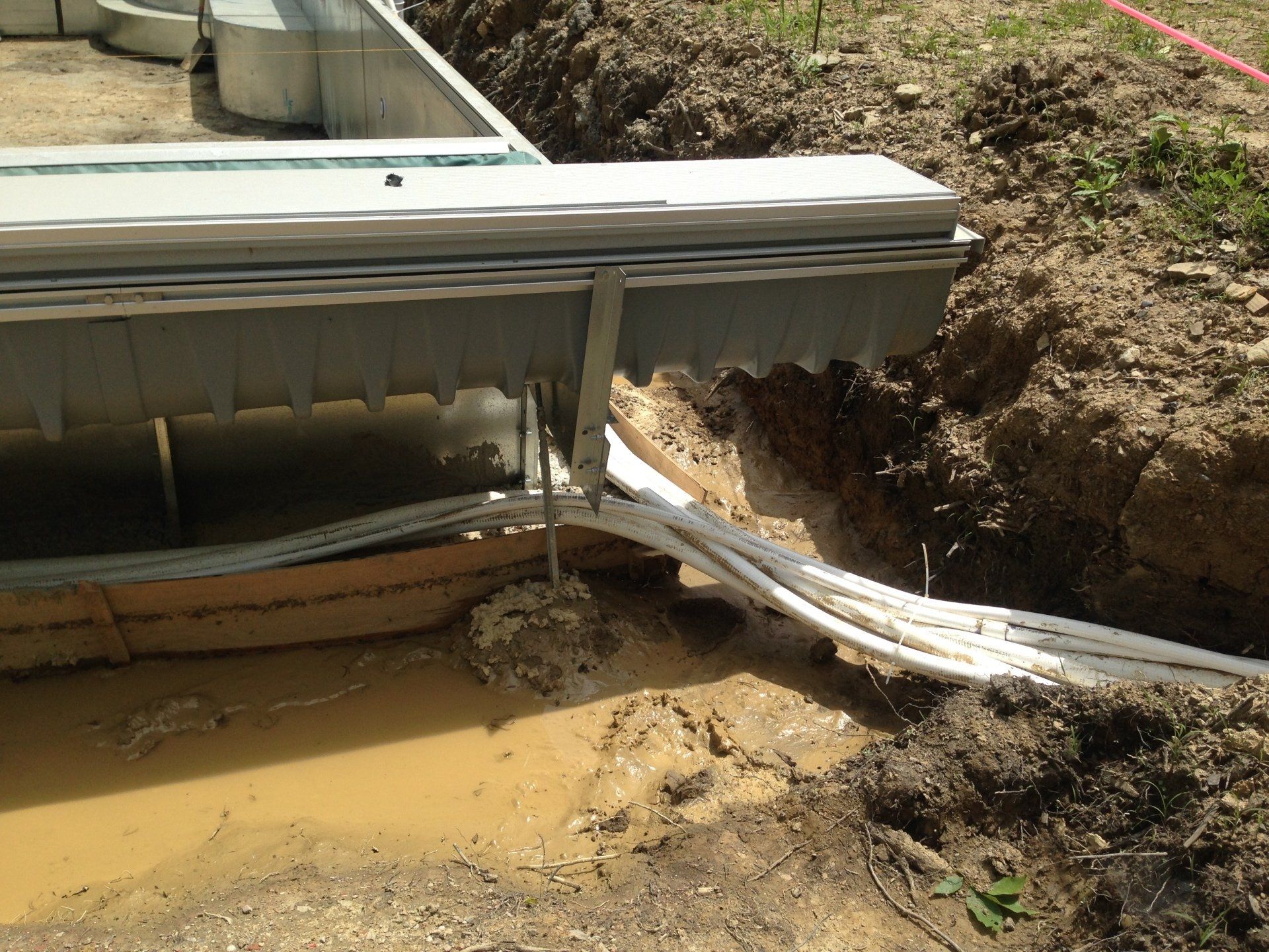 Collapsed metal structure over muddy erosion trench beside a yard