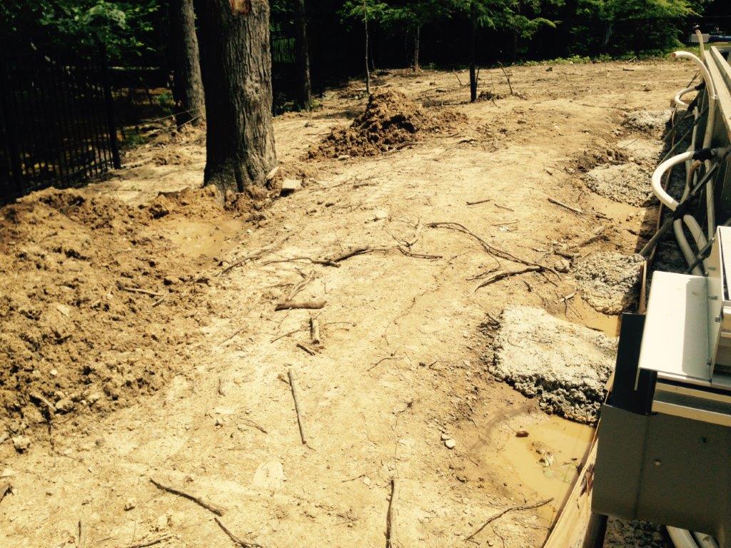 Dirt path beside trees and a fence, with a piece of outdoor equipment on the right
