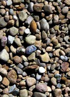 Close-up of small rounded pebbles in gray, tan, brown, and blue tones covering the ground
