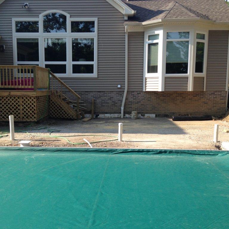 House exterior with large windows, deck stairs, and a covered pool in front