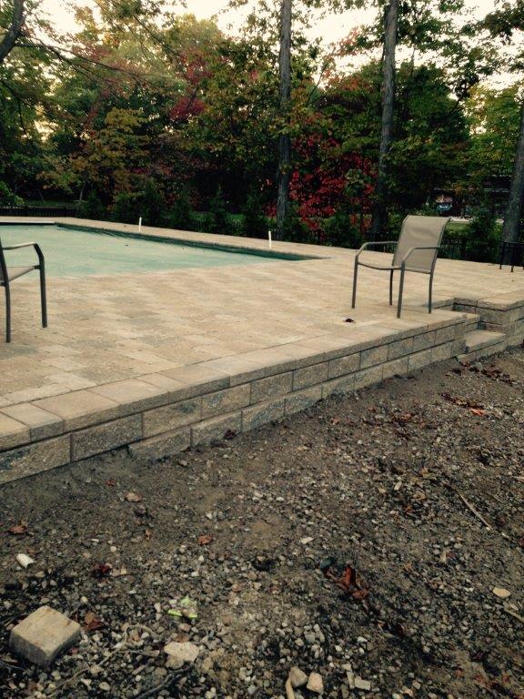 Empty outdoor pool deck with chairs, stone steps, and gravel in the foreground