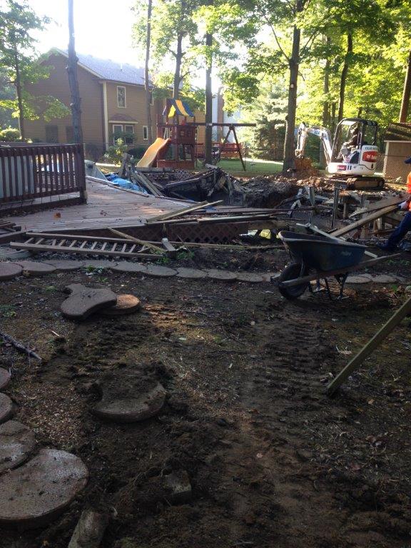 Burned backyard with charred debris, a collapsed deck, and a house in the background.
