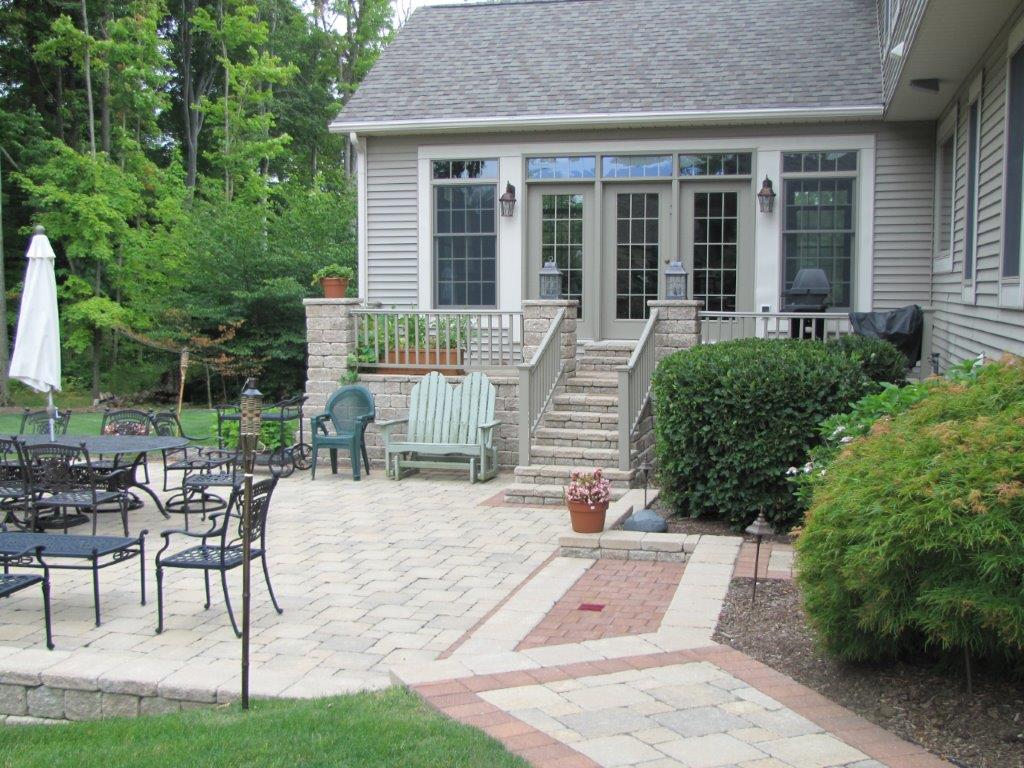 Patio with outdoor dining set, umbrella, and steps leading to a house with French doors and gray siding