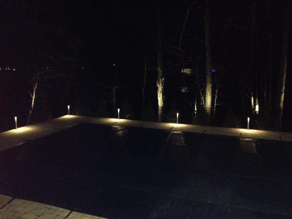 Dimly lit outdoor patio with ground lights and trees at night