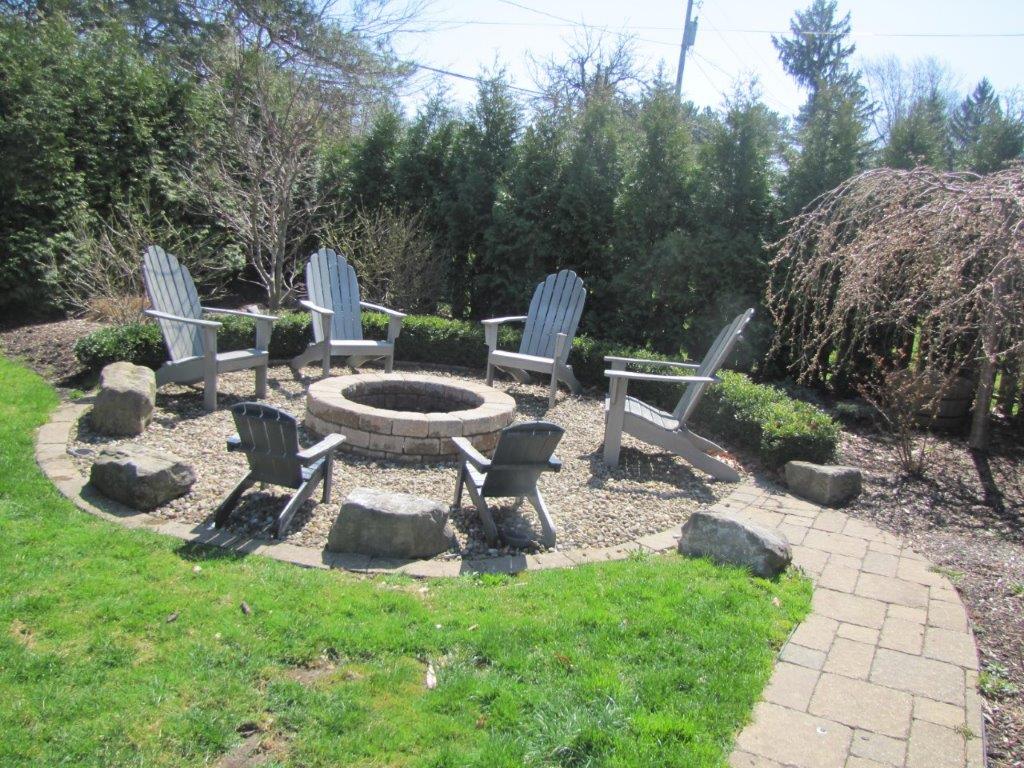 Stone fire pit with chairs in a sunny backyard garden