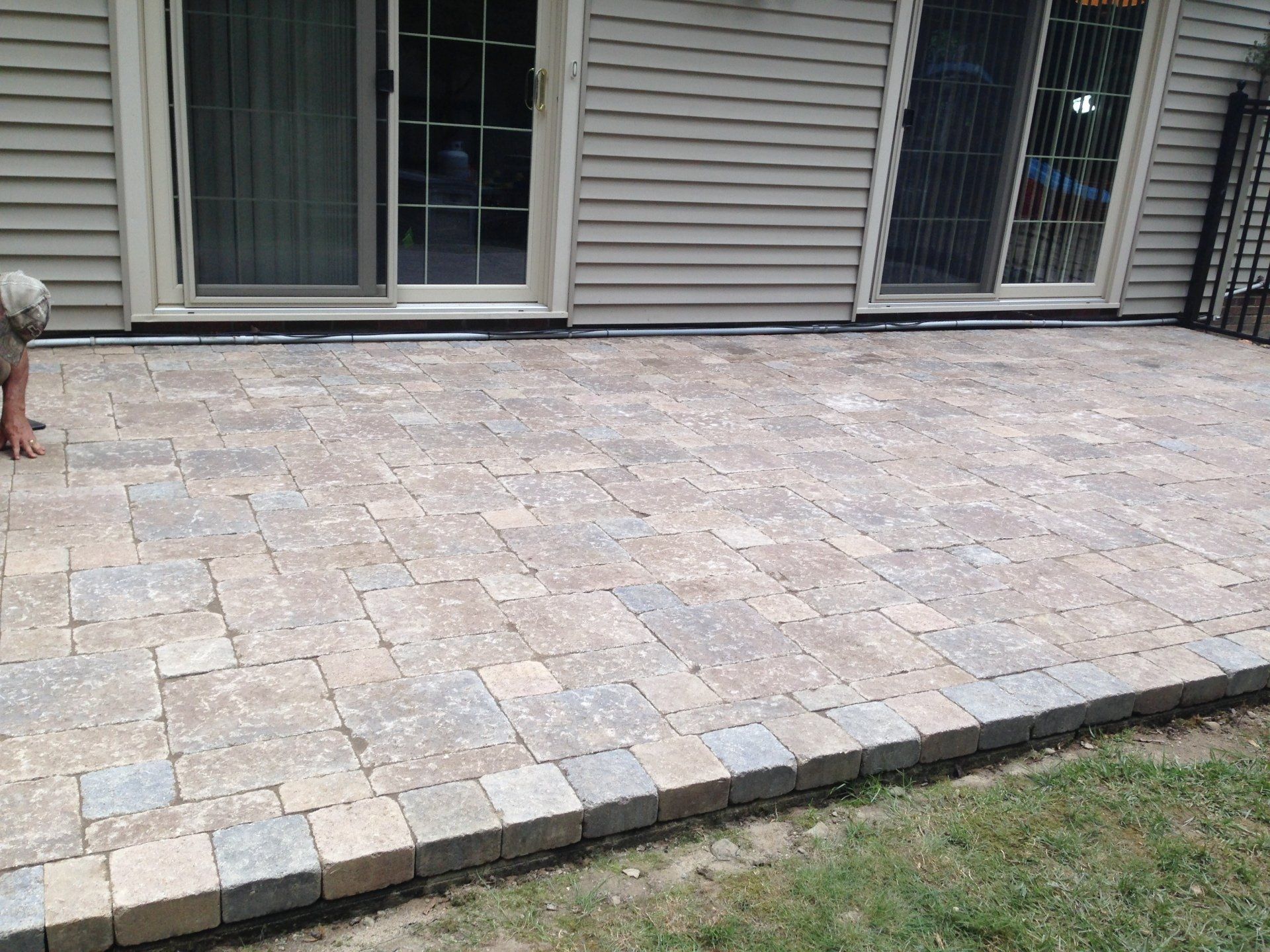 Stone patio beside sliding glass doors and house siding, with a small dog at the left edge.