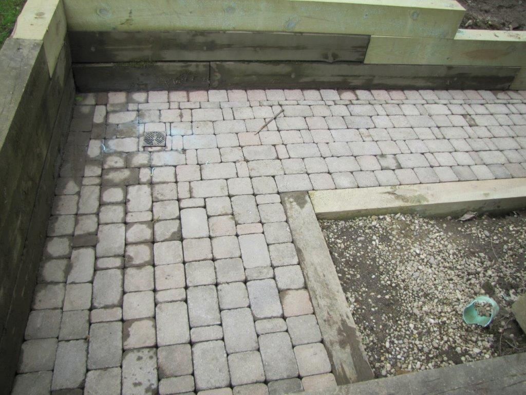 Stone-paved courtyard with raised concrete borders and a small gravel bed in the corner
