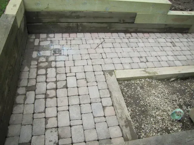 Stone-paved courtyard with a raised concrete border and gravel planter area