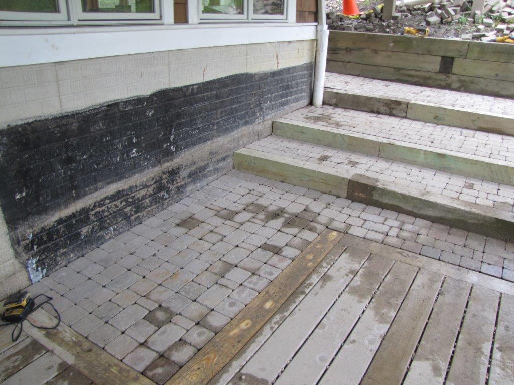 Stone steps beside a building entrance with a tiled landing and a wood ramp in the foreground