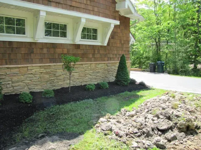 House exterior with new landscaping and a mound of dirt beside a driveway