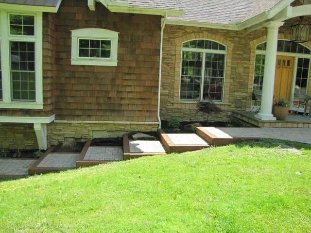House exterior with green lawn and a small wooden ramp leading to the front door