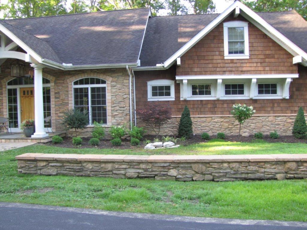 Brick-and-wood suburban house with a stone retaining wall and green lawn