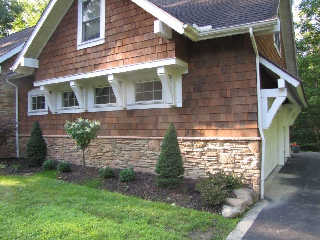 Brick house exterior with shingled upper walls, stone lower facade, and a driveway on the right