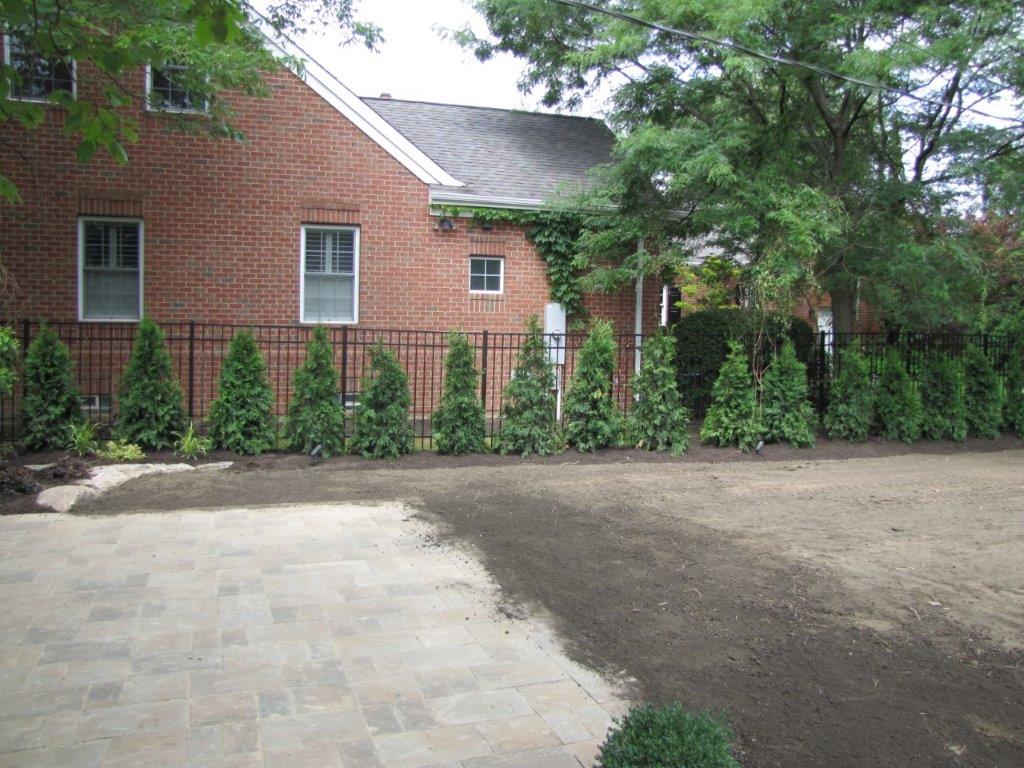 Brick house with red siding, front windows, and a driveway beside a tree-lined yard