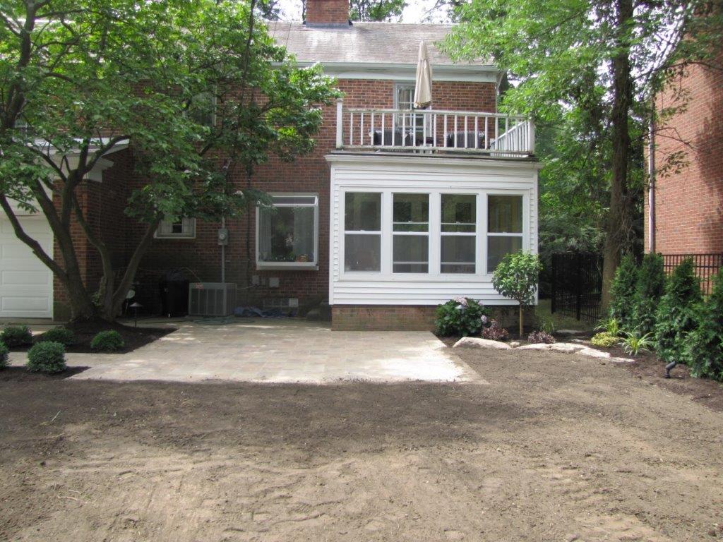 Backyard view of a house with a patio, white windows, and a dirt-covered yard
