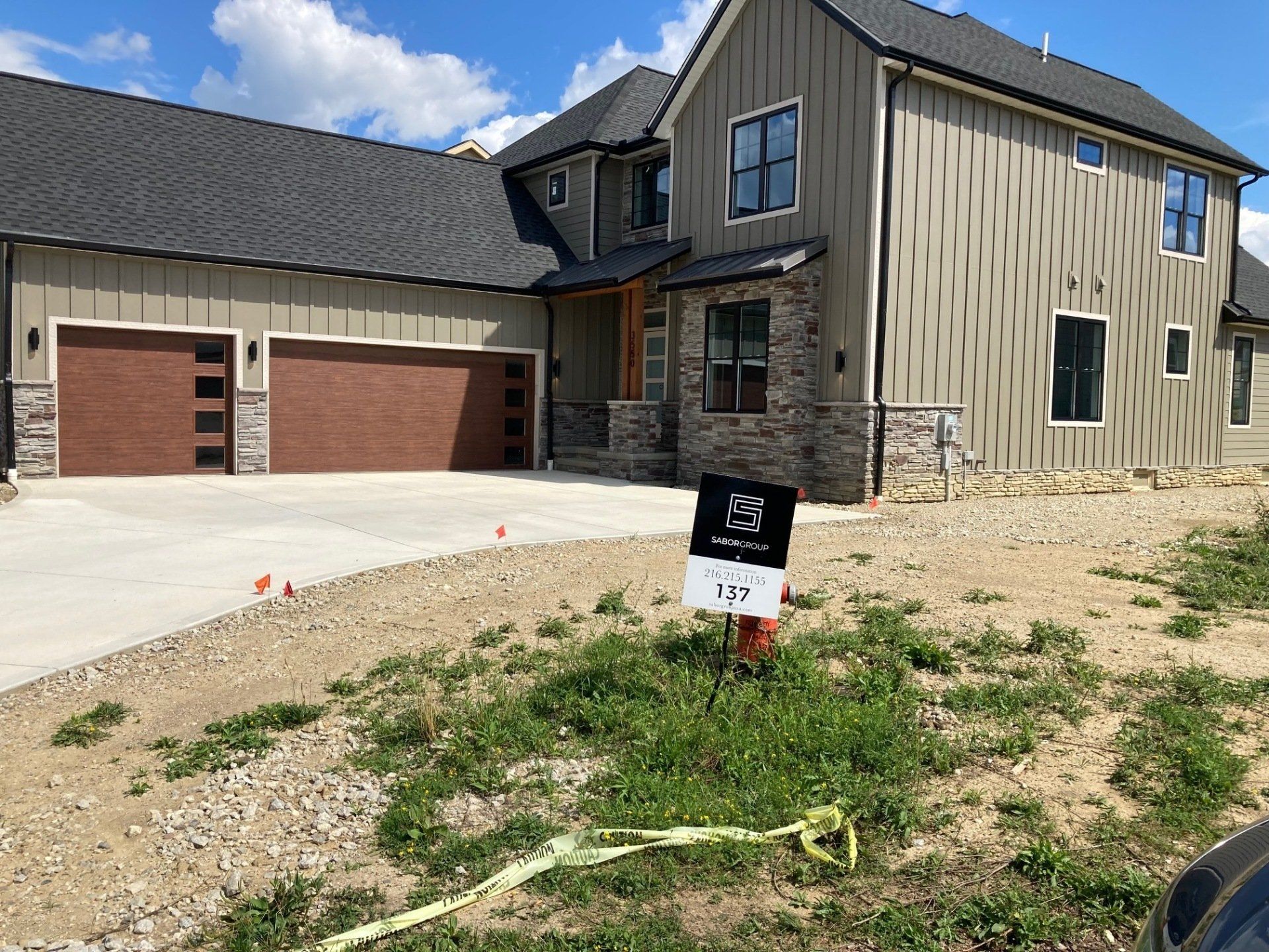 New house exterior with garage, gravel driveway, and for-sale sign in front yard