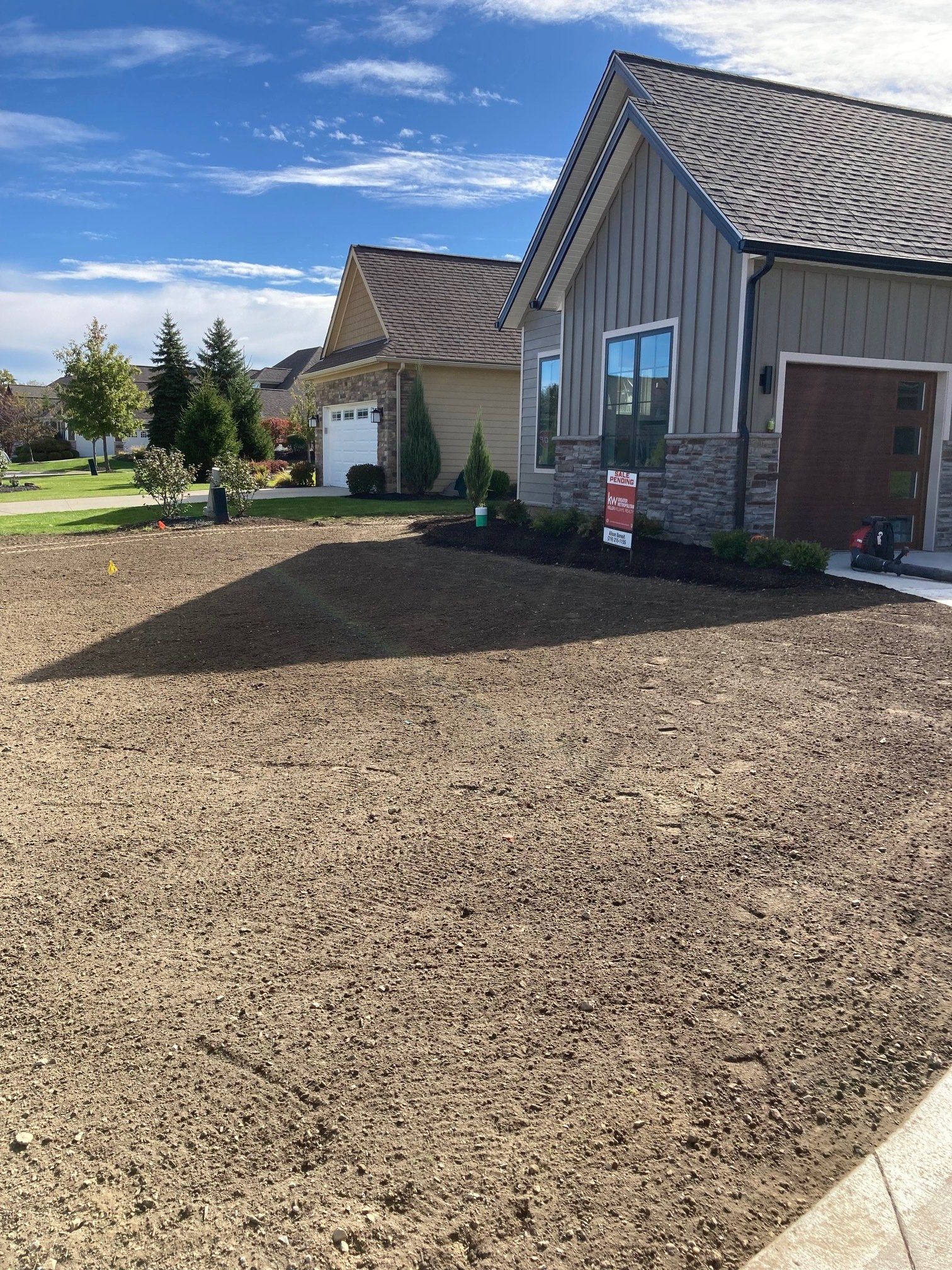 Newly landscaped front yard with gravel, modern houses, and a blue sky